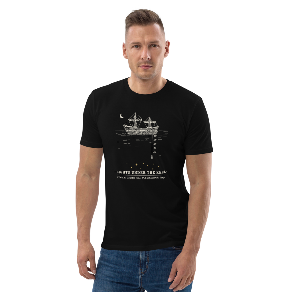 Model wearing the Lights Under the Keel tee in Black, the ship, lead line and nine gold lights at centre chest